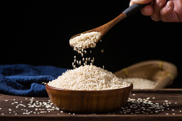 white sesame seeds in wooden spoon on table.