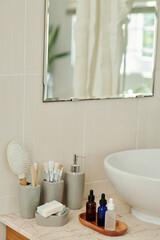 Vials with various serums and oils next to sink in bathroom