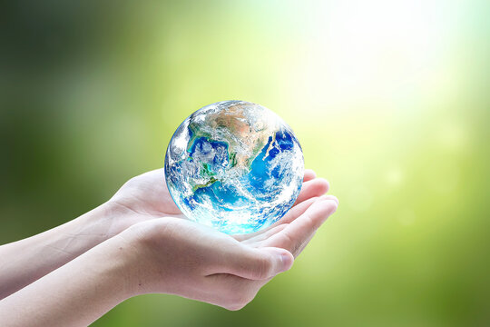 Human hands holding earth globe over blurred green nature background. Elements of this image furnished by NASA