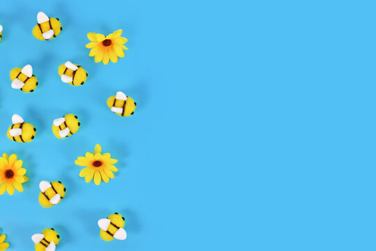 Cute felt bees and yellow flowers on side of blue background with copy space