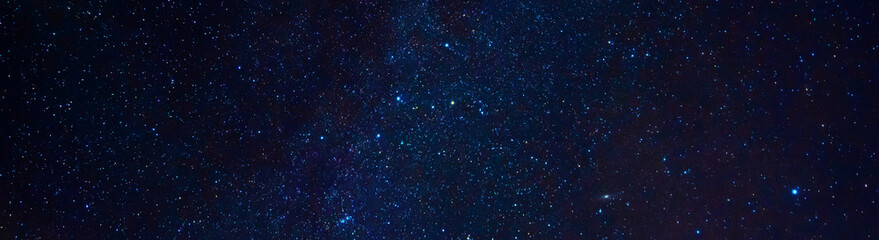 Fototapeta premium Astrophotography of a dark blue starry sky with many stars, nebulae and galaxies. Panoramic wide horizontal photo for banner head cover