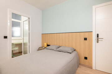 Fototapeta na wymiar Compact stylish bedroom in stylish soothing colors with double bed and door to an enclosed balcony with an office area. Confined space concept and interior solutions