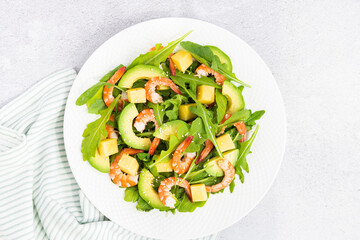 Flat lay of Healthy salad plate. Fresh seafood recipe. Grilled shrimps and fresh vegetables (avocado, arugula, mango) on gray concrete background. 