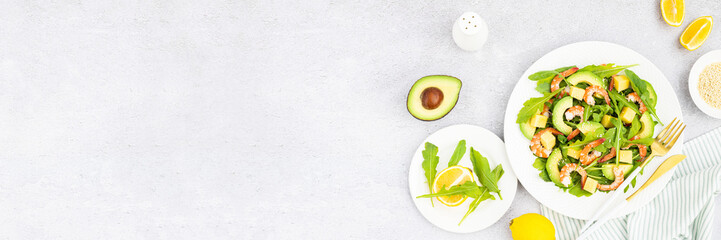 Flat lay of Healthy salad plate. Fresh seafood recipe. Grilled shrimps and fresh vegetables (avocado, arugula, mango) on gray concrete background. 