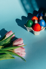 easter theme composition - coloured eggs and beautiful tulips on blue background