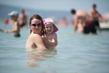 The family is bathing in the sea. Mother and daughter having fun in the ocean. Summer fun. 