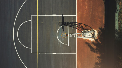 Aerial background basketball court, sports playground and outdoor community turf for competition, training and ball game. Above basketball hoop, floor space lines and urban stadium pitch in sunshine © Allistair F/peopleimages.com