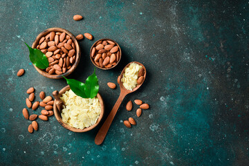 Obraz na płótnie Canvas A wooden bowl with almond slices. Almond chips. On a dark turquoise background. Copy space.