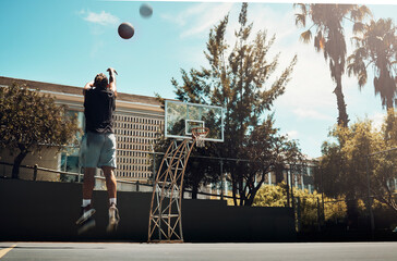 Basketball, outdoor and a man shooting ball alone on basketball court in Miami summer sun. Fitness, training and health, basketball player jumping to score on court at weekend sports game practice.