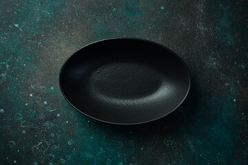 Oval slate black plate. On a dark green-turquoise background. Free space for text.