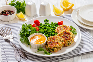 crab cakes with sauce, green peas, tomatoes