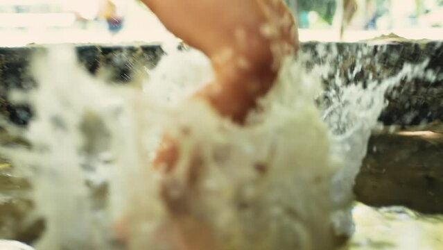 Playful kid splashing into water mud puddle at park. Child jumping into pool water