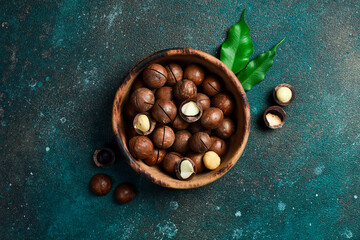 Macadamia nuts in wooden bowl on textured background. Copy space. Superfood, vegan, vegetarian food...