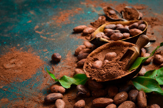 Cocoa beans and cocoa powder in a wooden bowl. On a dark background. Side view.