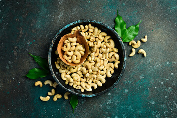 Cashew nut in a wooden bowl. Healthy snacks. On a dark background.
