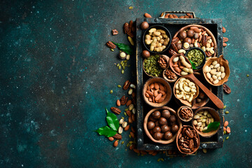 Assortment of nuts in a wooden box on a black background - healthy snack. Top view. Copy space
