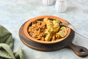 Ragout, stewed beef with cabbage and dough dumplings in a ceramic plate on a light concrete background. Cabbage recipes.