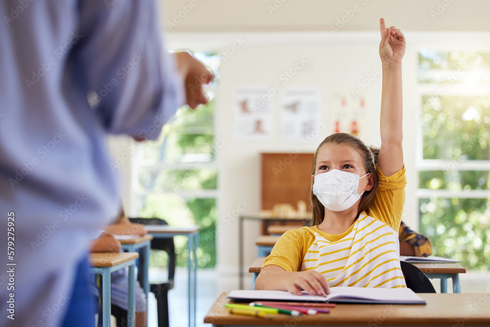 Wall mural Smart student with covid face mask asking teacher question about corona virus pandemic in a classroom or elementary school. Little girl child raising hand to answer healthcare related topic in class