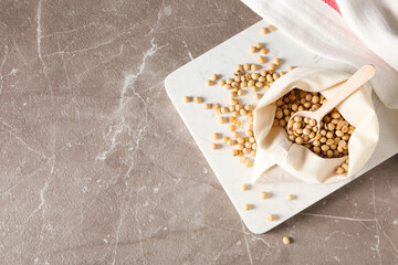Wooden spoon with soy seeds on gray textured table