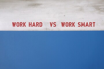 copy space blue and grey wall with text WORK HARD VS WORK SMART, means smart workers complete work within timelines using shortcut, proper planning or prior research  instead of working long hours