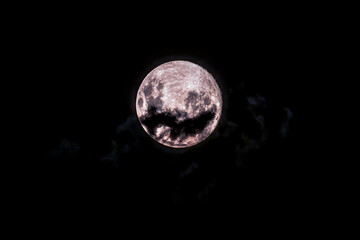 Earth's moon at 98 percent full with dark clouds drifting past in the dark smoky night sky