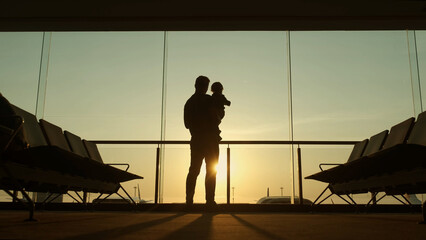 Silhouette of father and his little kid waiting for departure playing together in airport lounge...