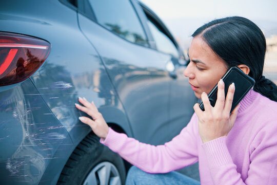 Woman calling car insurance examining car damage
