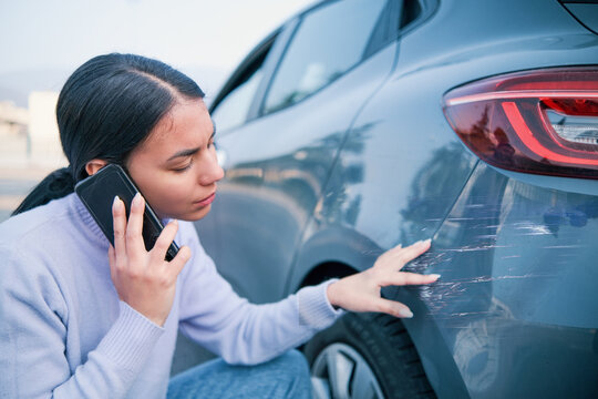Woman checking car damage after car crash