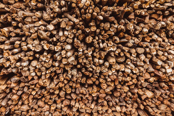 Close up on a pile of chopped wood for burning, with round logs and wedge timber stacked to form a background
