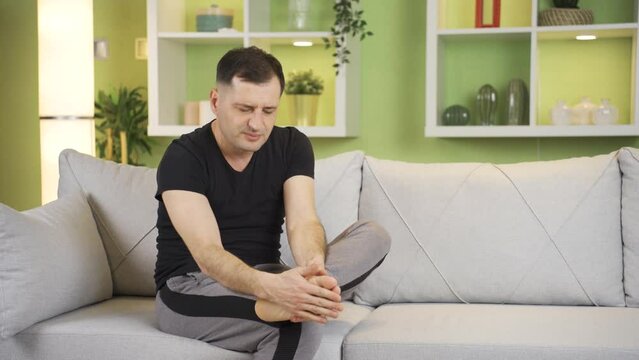Man with fungal foot condition, his feet are irritated, burning and hurting.
Man severely scratching his feet at home suffers, athlete's foot ailment.
