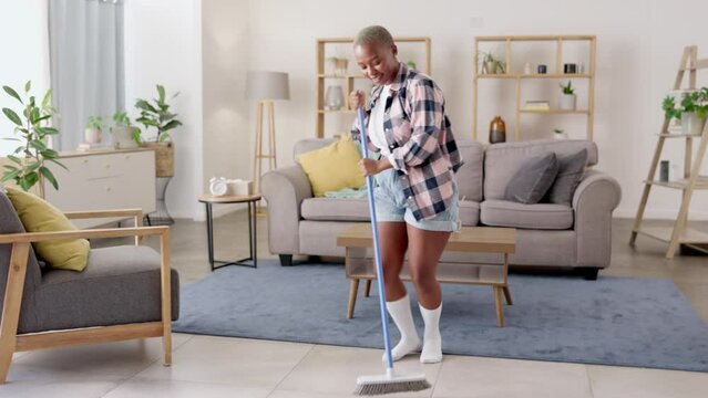 Singing, dancing or black woman cleaning and listening to dance radio music on living room floor with a broom. Dancer, fun cleaner or happy African female maid sweeping in a house, home or apartment