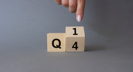 From 4th Quarter to 1st symbol. Businessman hand points at Turned wooden cube with words 4th Quarter and 1st Quarter. Beautiful grey background. Business and Quarter concept. Copy space