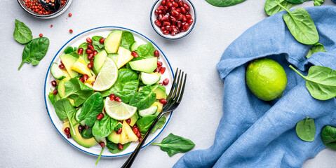 Fresh vegan salad with pineapple, spinach, avocado and pomegranate seeds, gray kitchen table, top view. Healthy eating, clean food, diet, weight loss concept