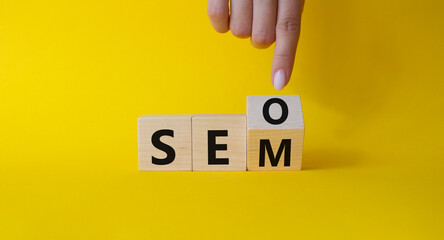 Seo and Sem symbol. Businessman hand points at turned wooden cubes with words Sem and Seo....