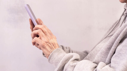 The hands of an elderly woman are holding a phone.