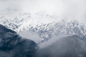 A snow capped Himalayan mountain covered with mist and fog on a cloudy day in Munsyari in...