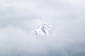 Fototapeta na wymiar A snow capped Himalayan mountain peak surrounded by clouds in the Kumaon region of Uttarakhand.