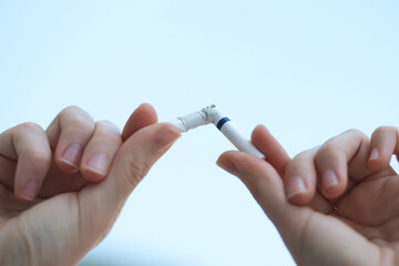 Stop smoking, quit smoking or no smoking cigarettes. Woman holding broken cigarette in hands. Woman refusing cigarettes. Quit bad habit.