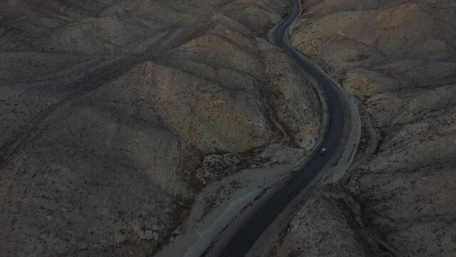 Aerial Tilt Up Reveal Sunset On Horizon Over RCD Road Through Remote Balochistan Dramatic Landscape. Dolly Forward 