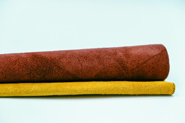 Genuine leather pieces isolated on white background. Yellow and red genuine leather rolls. Real leather surface. Hobby and craft material. Manufacture, background textured and wallpaper
