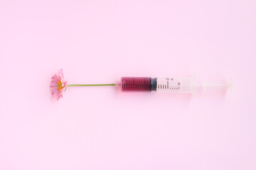 Injection Syringe with Pink Chrysanthemum flower on pink background, Beauty injections concept.