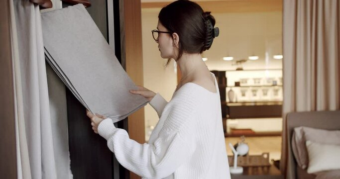 Young woman chooses curtains in the store. Female hand choosing fabric cloth for curtain at showroom or shop. Examining fabric in a drapery store. customer hands