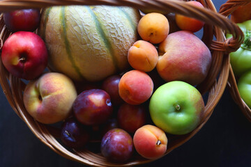 Two wicker baskets with healthy seasonal fruit and vegetable. Dark background, top view.