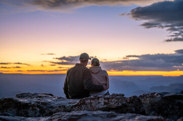 Wedding couple embracing sitting on the edge of the cliff of the grand canyon watching the sunset and sunset
