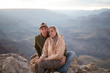 Portrait of a wedding couple hugging sitting on the rock at the edge of the cliff in Grand Canyon...