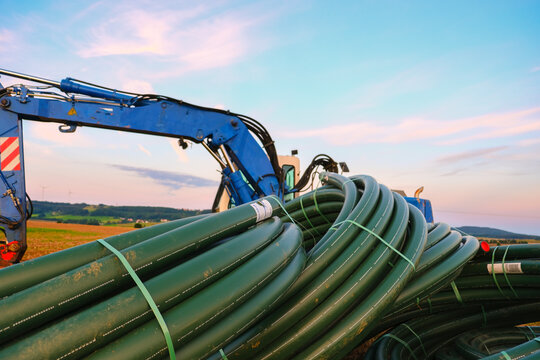 Water pipes and construction installation equipment in the field.Technique and equipment for water supply. Carrying out water construction work.Plumbing installation.Blue excavator with pitchforks