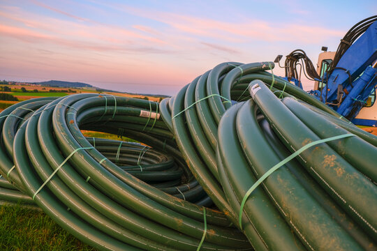 Plumbing installation.Blue excavator with pitchforks. Technique and equipment for water supply.Water pipes and construction installation equipment in the field.Carrying out water construction work.