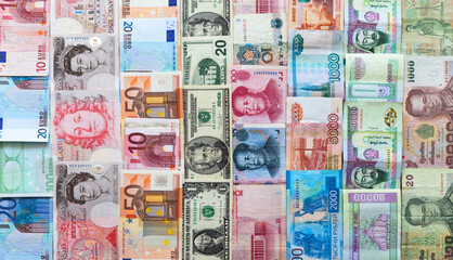 Currency of different countries in paper banknotes of various denominations is laid out in rows on table: dollars, euros, pounds, yuan, tugriks, rubles, won, baht. International cooperation  - obrazy, fototapety, plakaty