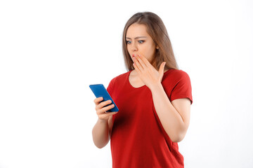 Portrait of lovely young woman using mobile phone, texting message, watching on smartphone, looking impressed with disbelief, standing over white background