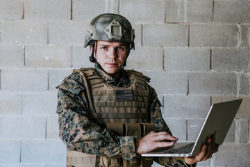 American soldier in military uniform using laptop computer for drone controlling and to stay in...